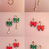 A grid of six pairs of interchangeable dangle earrings on a pink background, featuring gold-plated c-hoops, gold hoops with freshwater pearls, green and red bow charms, and playful combinations of bows and pearls.