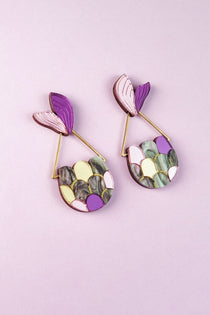 Two colorful Mermaid Tail Earrings with purple, pink, yellow, green, and marbled scales add whimsical elegance—perfect for mermaid lovers—displayed on a light purple background.
