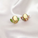 Minimalist Geometric Stud Earrings featuring gold centers and semi-circular marbled green, brown, and purple acrylic accents, displayed on smooth white satin fabric.
