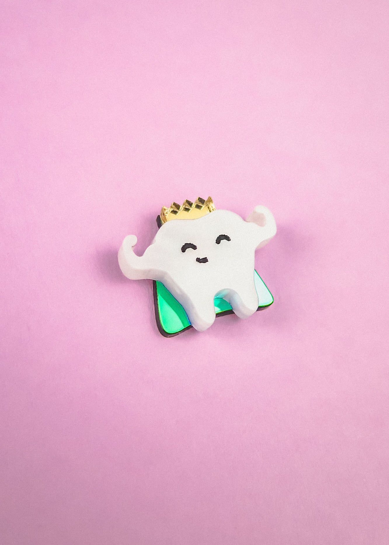 A cute Tooth King Pin enamel pin featuring a smiling, crown-wearing tooth with raised arms, set against a pink background—a charming handcrafted accessory for any collection.